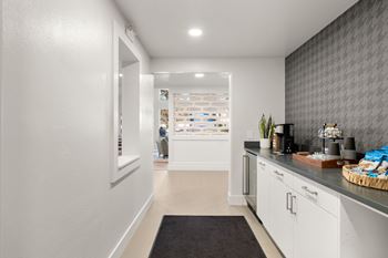 A hallway with a black rug on the floor leading to a kitchen area.
